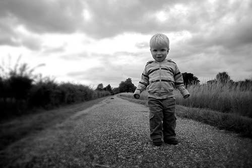 A little boy stands in a dusty country road
